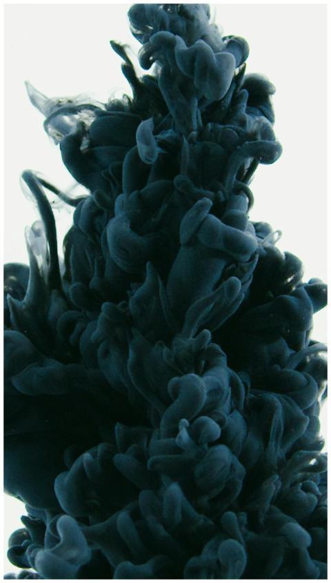 Close-up of black ink swirling in water, creating