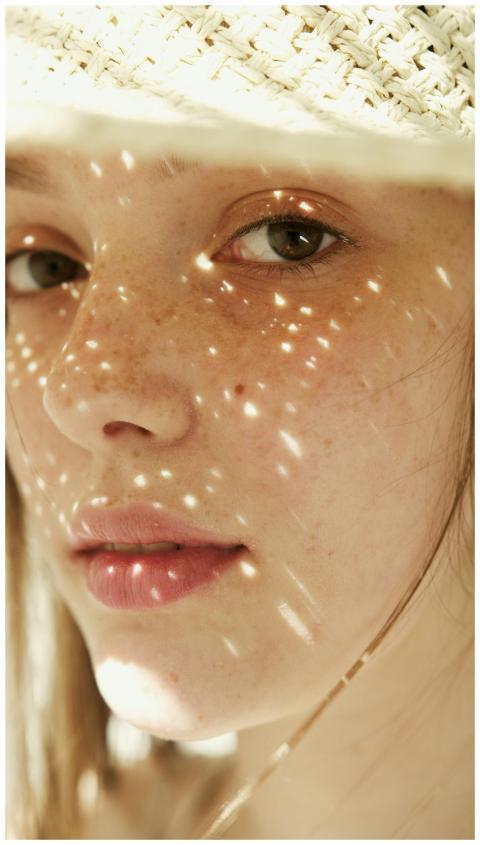 Close-up of a woman with freckles wearing a hat, s