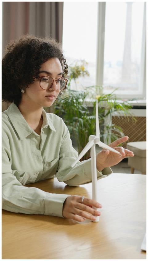 Focused young woman studying a wind turbine model
