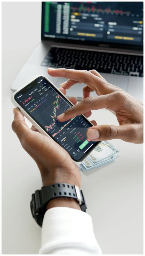 Hands using smartphone trading app with charts, do