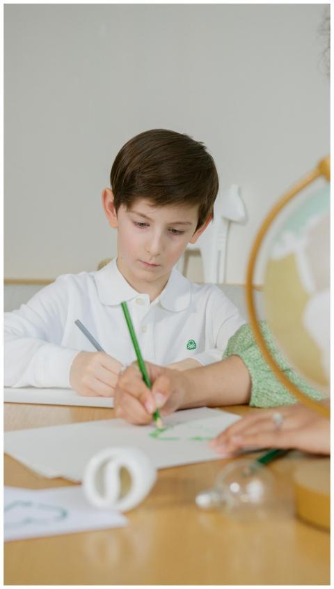 Young boy concentrates on writing task indoors at