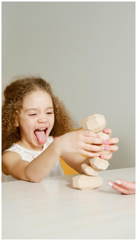 A happy child with curly hair plays with wooden bl