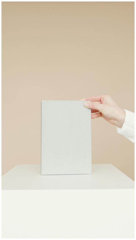Simple minimalist image of a blank book being held