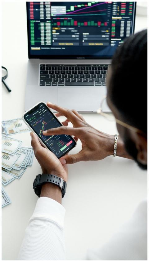A person trading stocks using a smartphone, showca