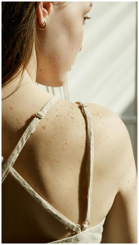 A close-up view of a woman's freckled back bathed