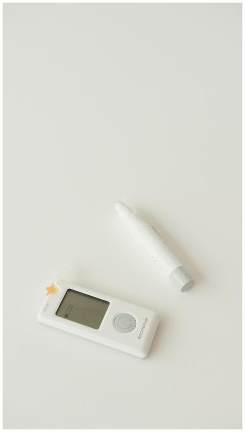 A digital glucometer and pen set against a minimal