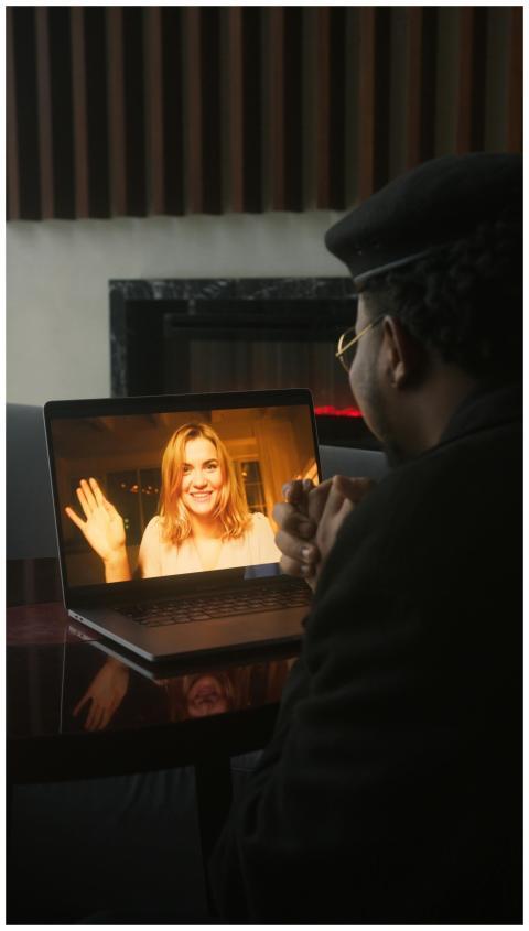 A virtual video call with a woman smiling and wavi
