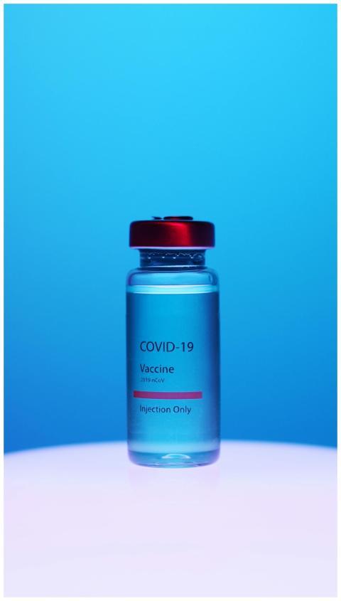 Close-up of a COVID-19 vaccine vial with red cap o