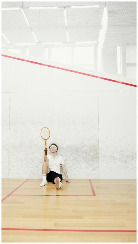 A squash player in sportswear sitting and resting
