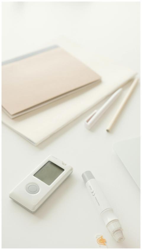 Close-up of a glucometer and lancet pen on a desk,