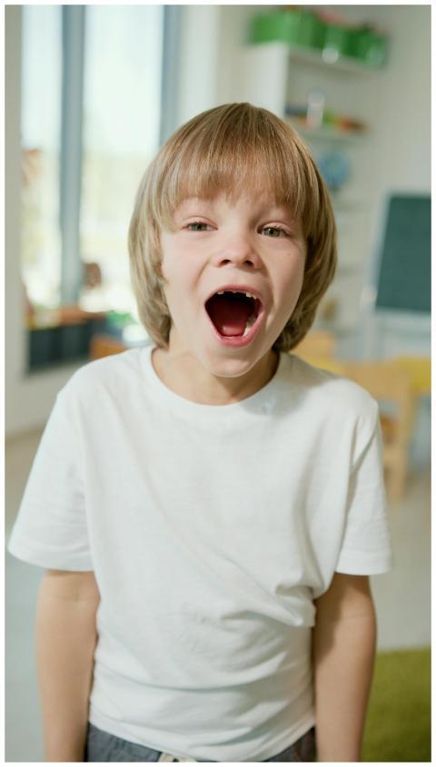 A joyful child with blonde hair laughing in a clas
