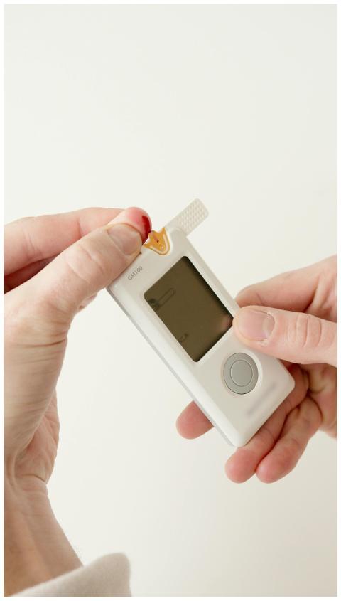 Close-up of hands using a glucometer for diabetes