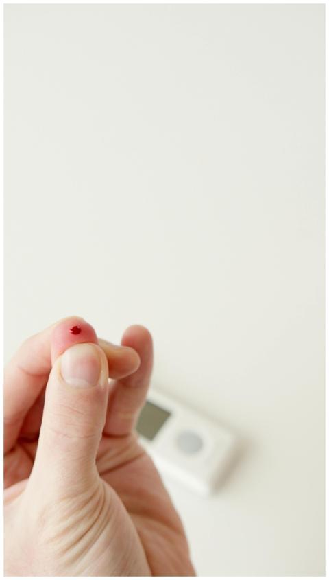 Close-up image of a finger prick with visible bloo
