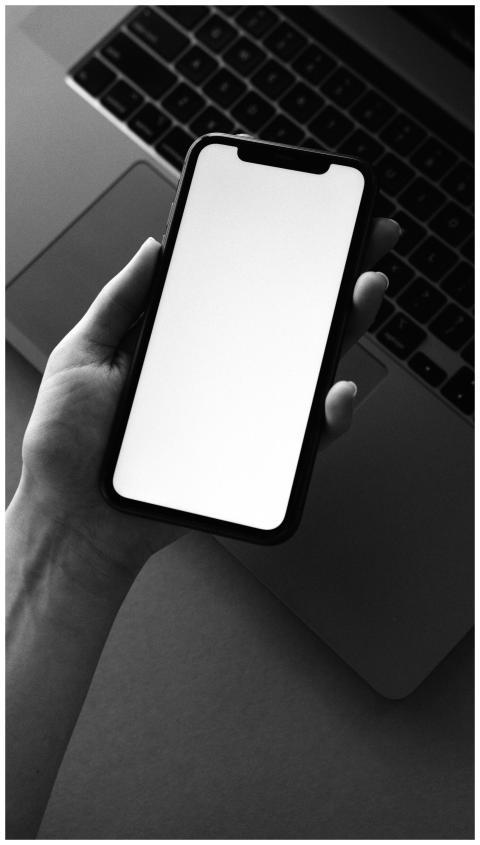 Monochrome photo of a smartphone held over a lapto