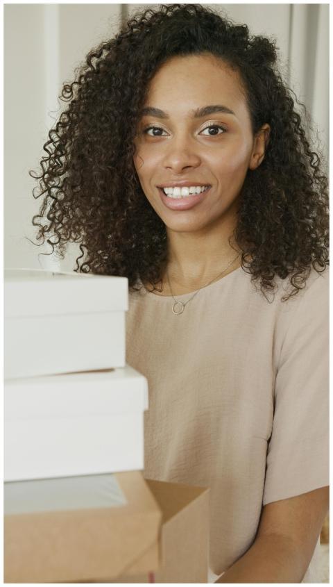Confident woman with curly hair smiling amidst pac