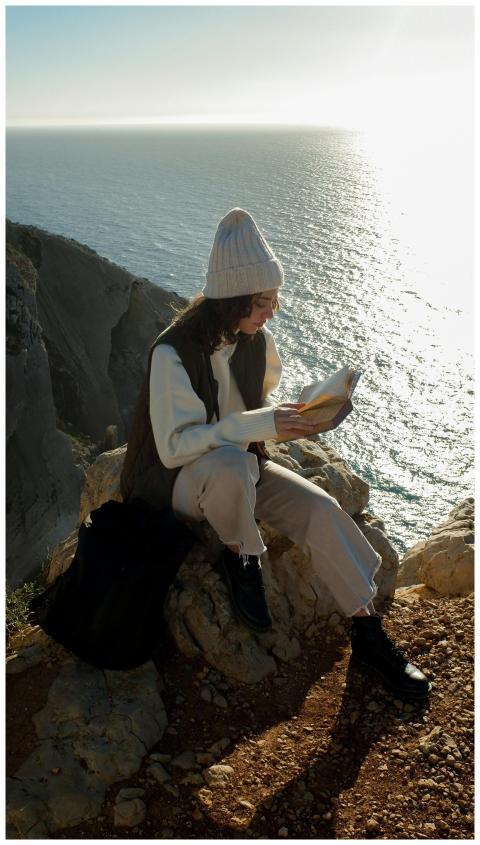 A woman enjoys reading a book on a cliff in Sesimb