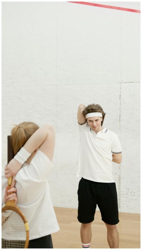 Two tennis players warming up by stretching on an