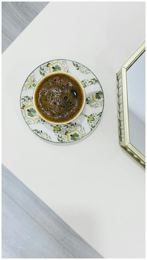 Top-down view of coffee in a floral saucer near a