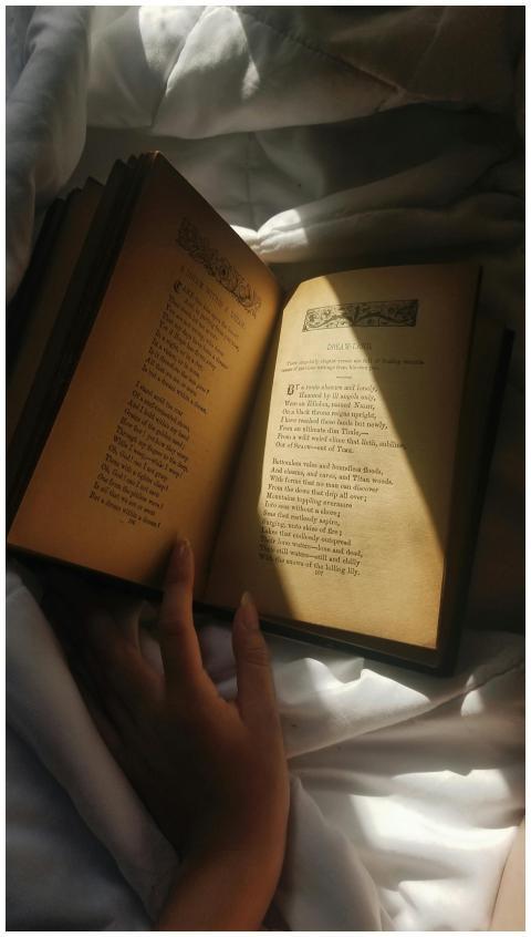 A hand gracefully holds an open book, revealing po