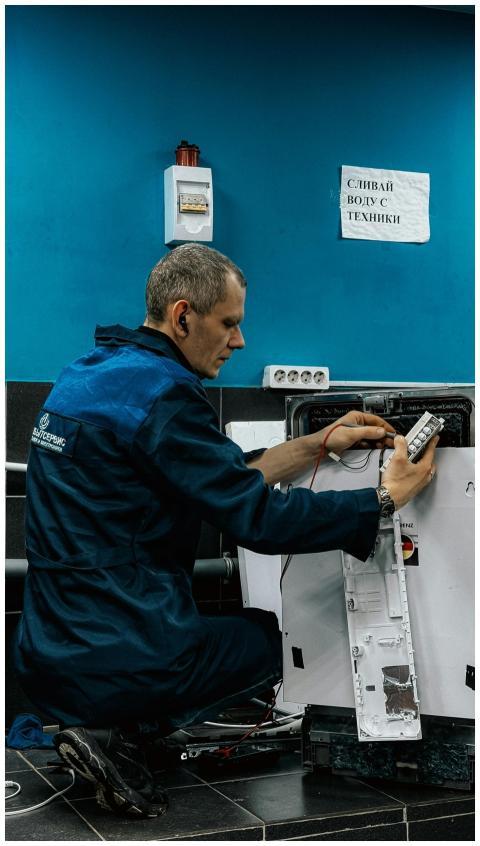 A focused technician in blue uniform repairs a hom