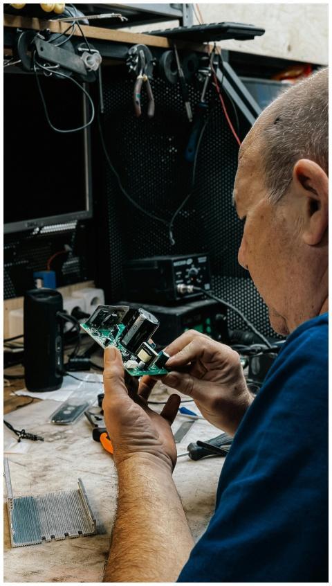 Technician fixing electronics amidst tools and gad