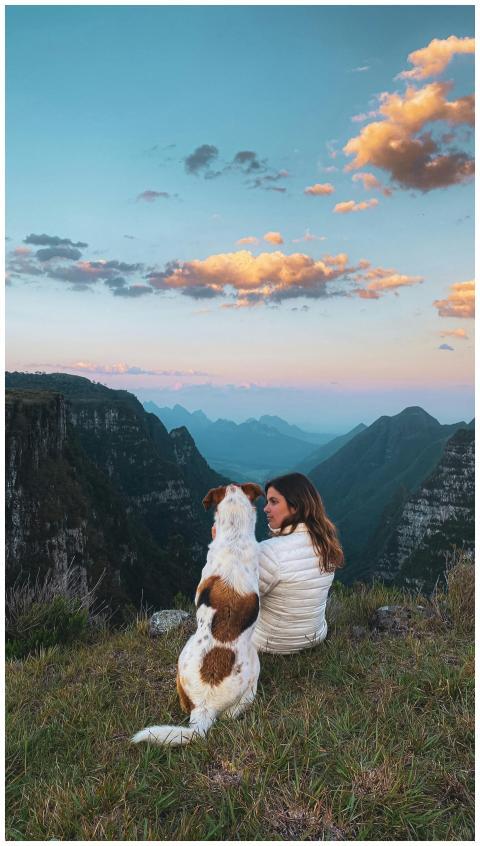 A woman and her dog enjoy a sunset view over the r