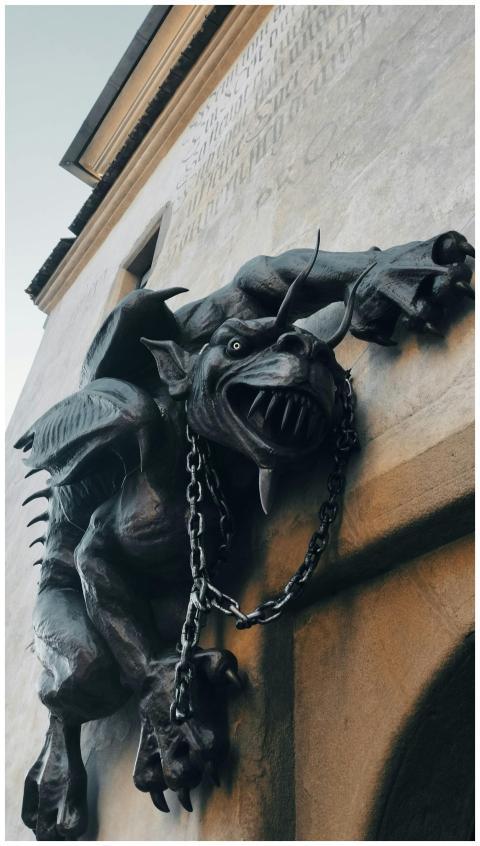 A fierce gargoyle statue clings to a building faca