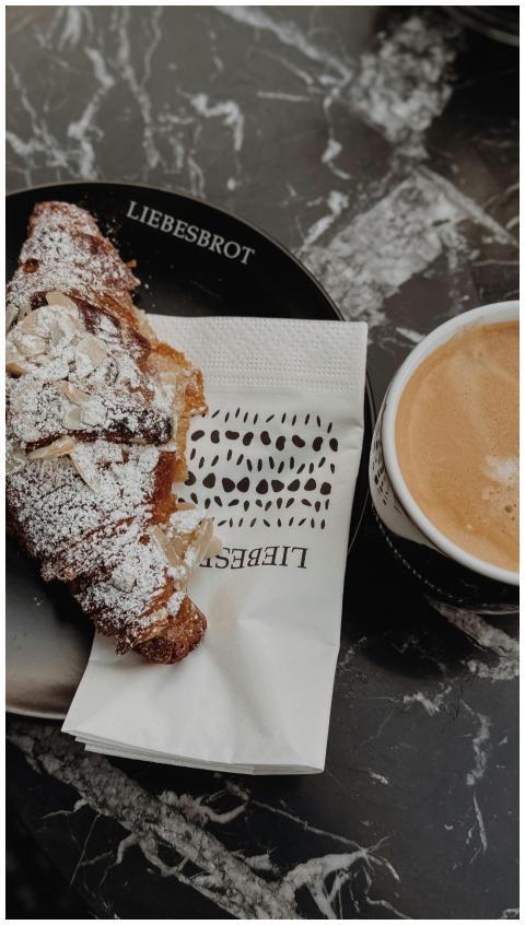 Almond croissant and cappuccino placed on a marble