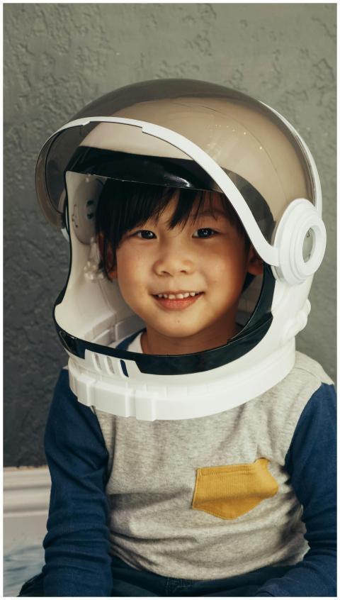 A smiling young boy wearing a toy astronaut helmet