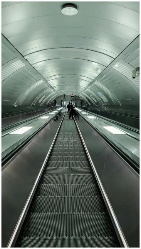 Long escalator in a modern metro station with urba