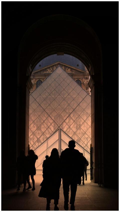Silhouette of people walking through an archway to