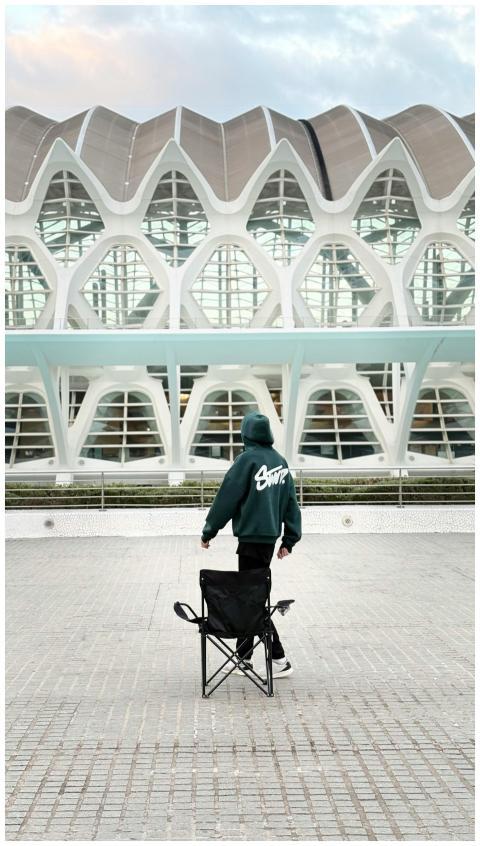 Person standing with chair in front of unique arch
