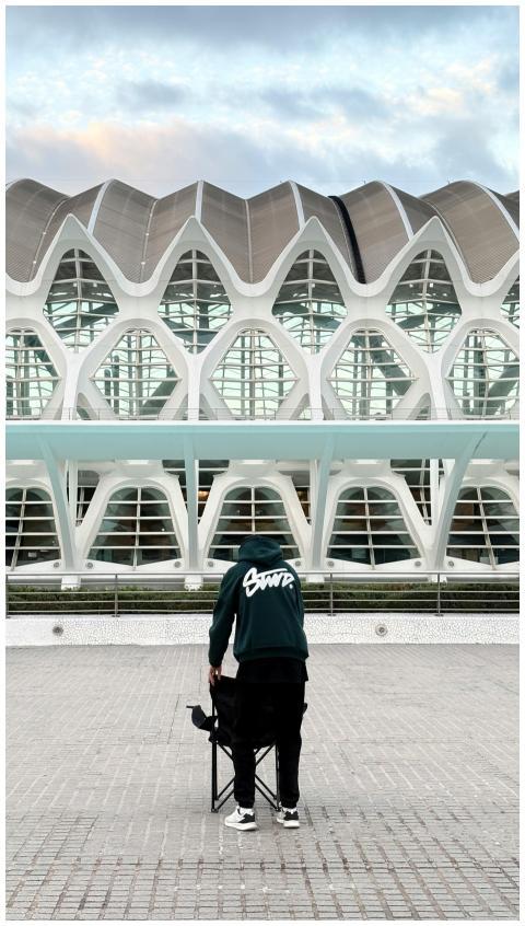 Person sets up chair against modern building facad