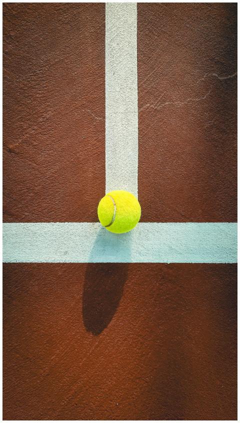 Tennis ball on a clay court highlighting its vibra