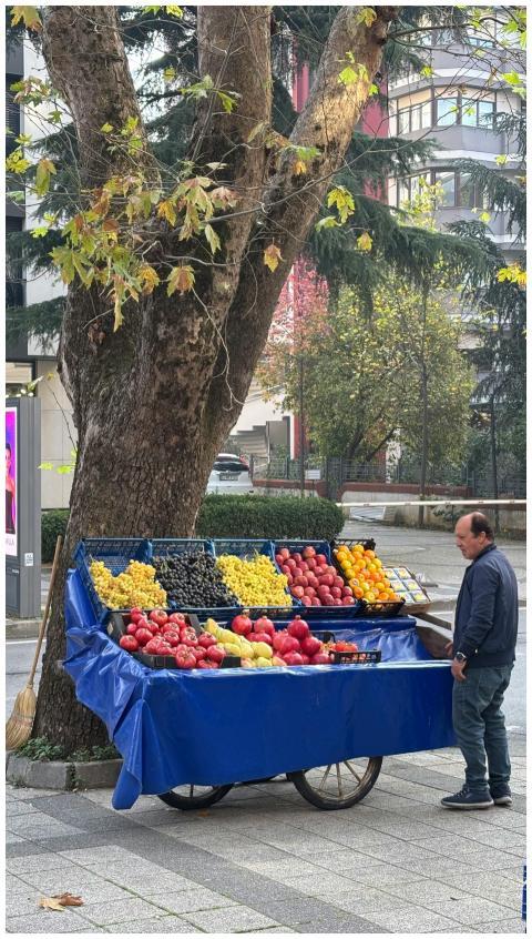 A street vendor sells fresh fruits from a cart und