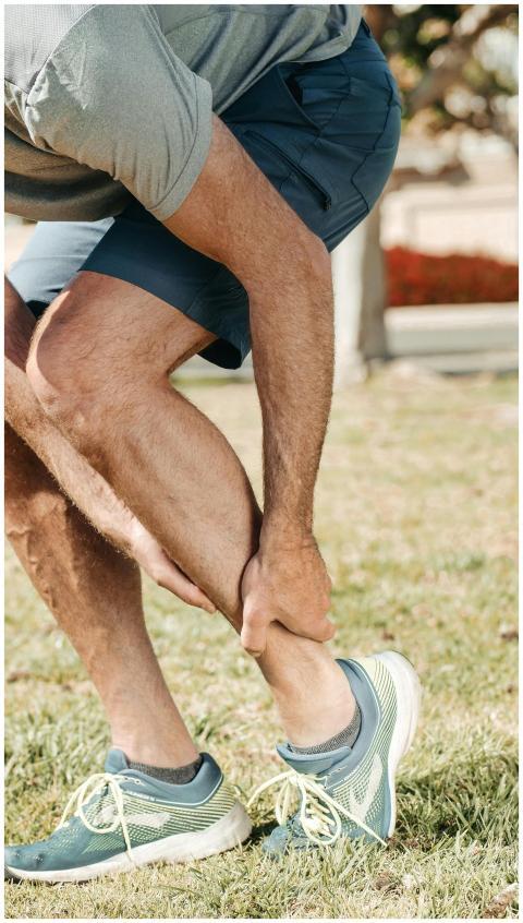 Adult male grabbing ankle due to injury in outdoor