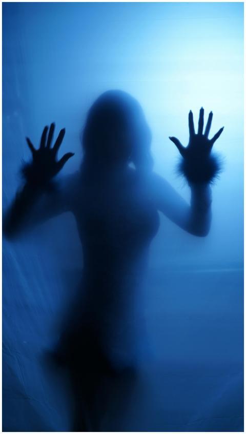 Silhouette of a woman pressing hands against fogge