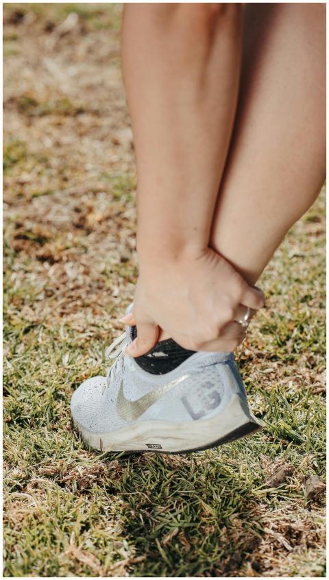 Close-up of a person holding their ankle in a snea
