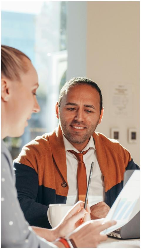 Two professionals discuss ideas in a sunlit modern