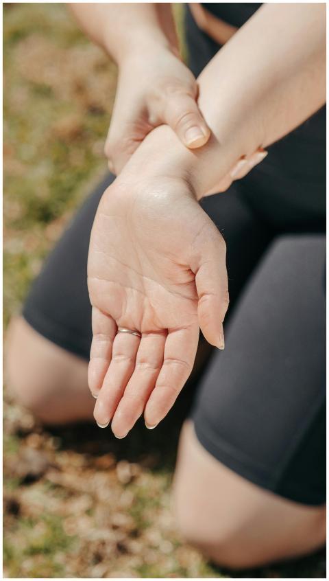 Close-up of a woman's hand holding her wrist outdo