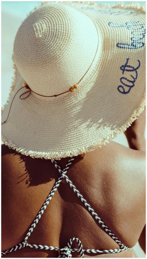 Back view of a person wearing a sun hat and swimsu