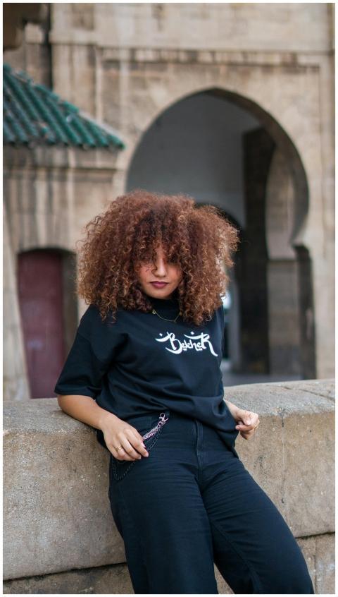 Stylish young woman poses against Moroccan archite