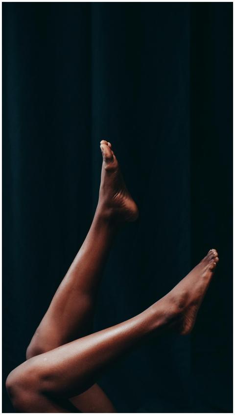 Close-up of two bare legs crossed against a black