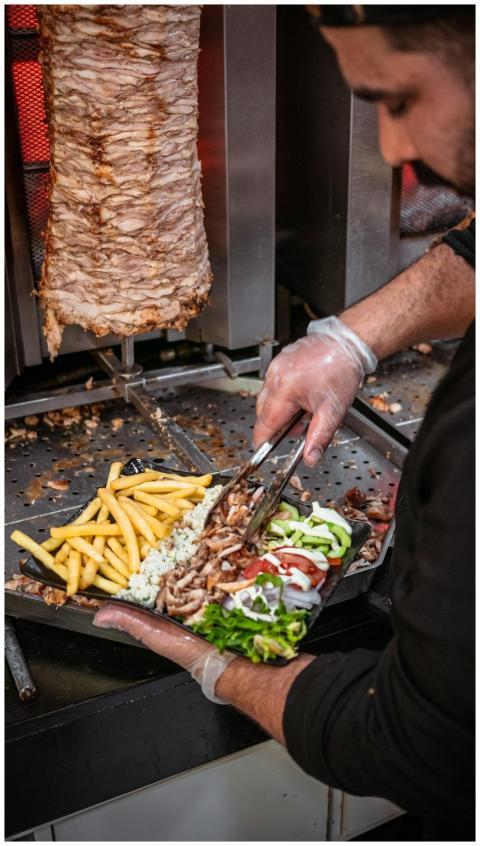 Chef preparing shawarma with fries and salad, show