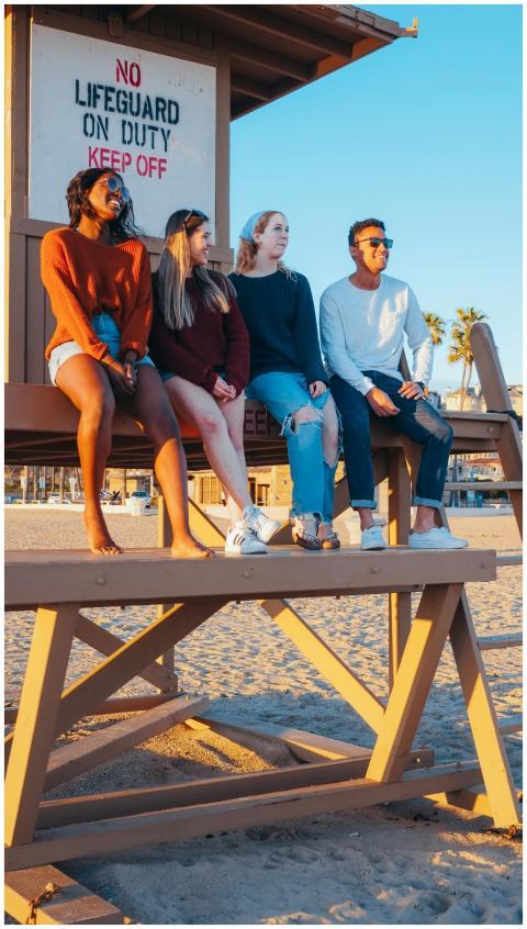 Multicultural group of friends sitting by a lifegu