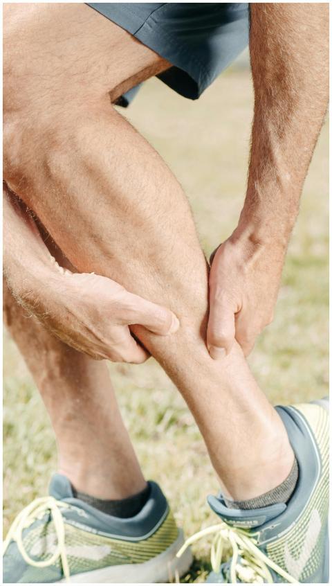 A man outdoors massaging his calf, dealing with mu