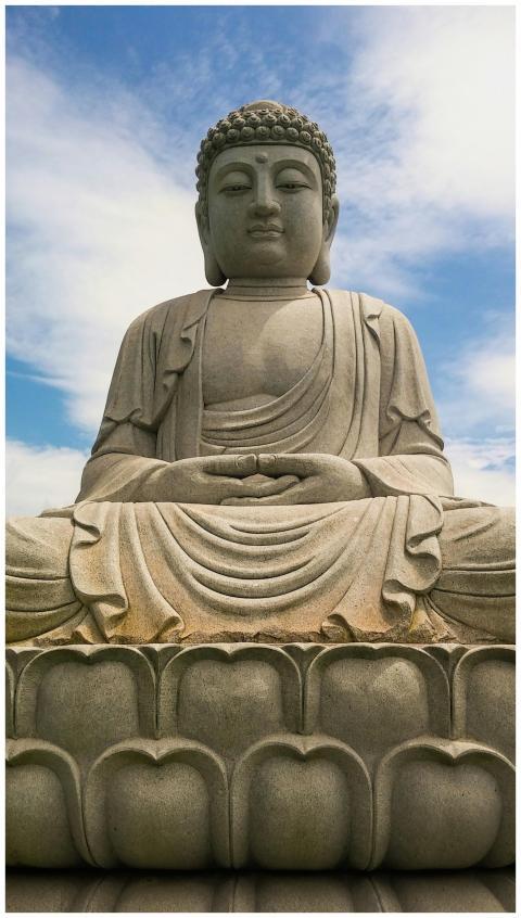 A peaceful Buddha statue beneath a clear blue sky,