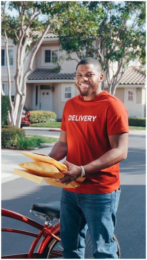 A friendly delivery man holding parcels outdoors n