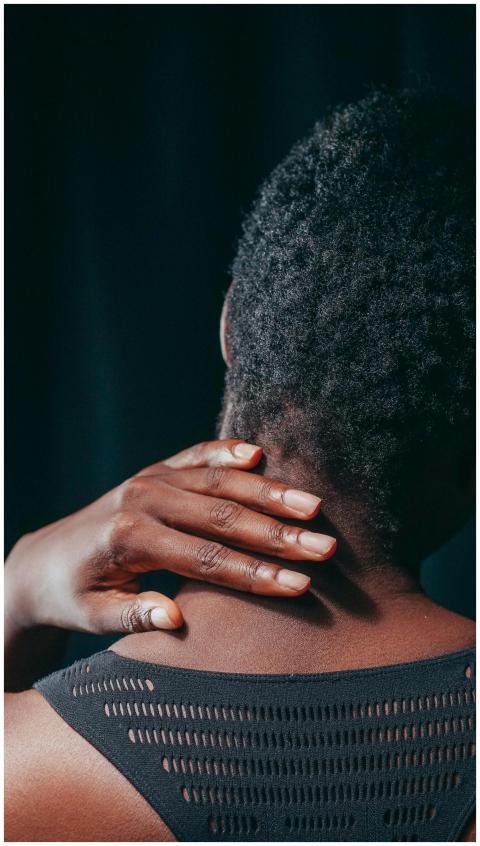 Close-up of a person touching their neck, indicati