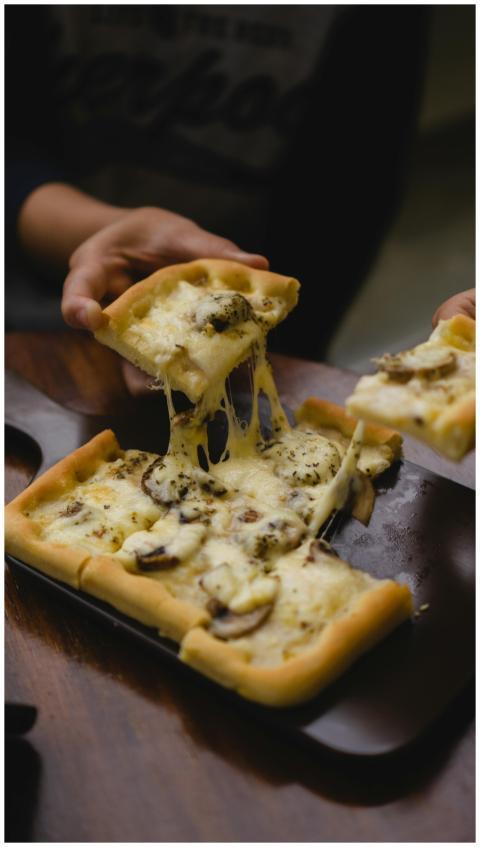 Close-up of a mushroom and cheese pizza slice bein